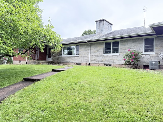 909 Randolph Rd, Middletown, CT 06457 - back of property featuring a lawn, stone siding, a chimney, central air condition unit, and roof with shingles