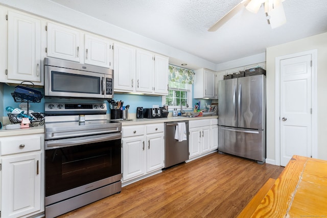825 Copper Hill Rd, Suffield, CT 06093 - kitchen with stainless steel appliances, light countertops, light wood-style flooring, white cabinets, and a textured ceiling
