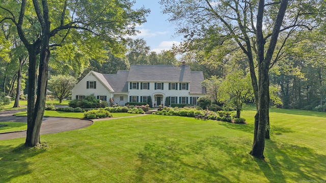 19 Father Peters Ln, New Canaan, CT 06840 - colonial home featuring a front lawn, a chimney, and view of wooded area