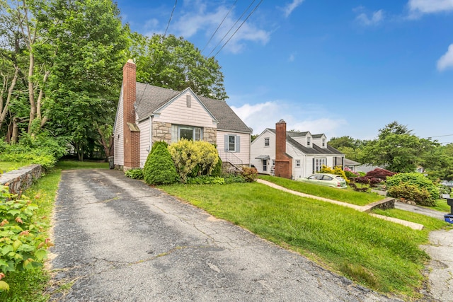 214 Thames St, New London, CT 06320 - view of front of home with a chimney, driveway, a front yard, and stone siding