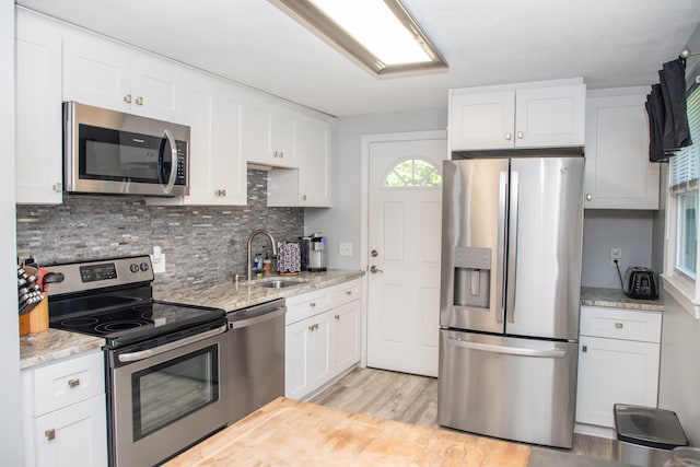 158 Jones Dr, New Britain, CT 06053 - kitchen with stainless steel appliances, a sink, tasteful backsplash, white cabinetry, and light wood-style flooring