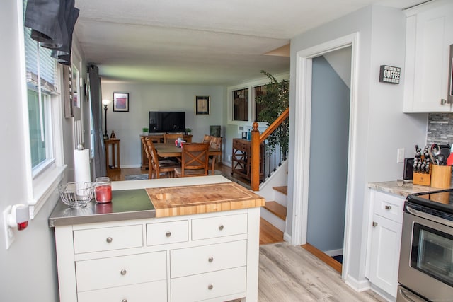 158 Jones Dr, New Britain, CT 06053 - kitchen featuring stainless steel electric range oven, light countertops, light wood finished floors, white cabinets, and open floor plan