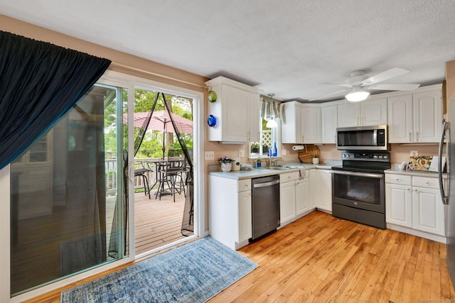 61 Pine Rd, Suffield, CT 06093 - kitchen featuring stainless steel appliances, a sink, light countertops, light wood-type flooring, and white cabinetry