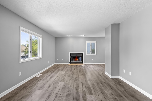 601 Whetstone Mls Unit 601, Killingly, CT 06241 - unfurnished living room featuring wood finished floors, a warm lit fireplace, a textured ceiling, and baseboards
