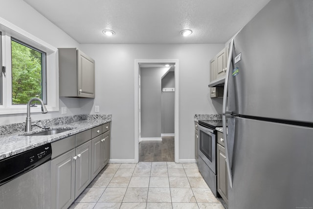 601 Whetstone Mls Unit 601, Killingly, CT 06241 - kitchen featuring stainless steel appliances, gray cabinetry, a sink, under cabinet range hood, and light stone countertops