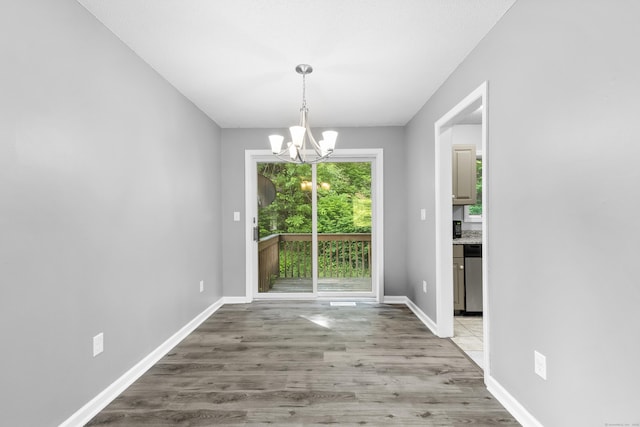 601 Whetstone Mls Unit 601, Killingly, CT 06241 - unfurnished dining area with a chandelier, light wood-style flooring, and baseboards