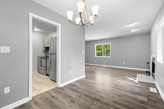 601 Whetstone Mls Unit 601, Killingly, CT 06241 - unfurnished living room featuring a chandelier, light wood-style flooring, baseboards, and a fireplace with flush hearth