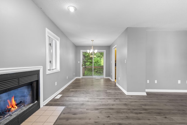 601 Whetstone Mls Unit 601, Killingly, CT 06241 - unfurnished living room with a chandelier, a fireplace with flush hearth, wood finished floors, and baseboards