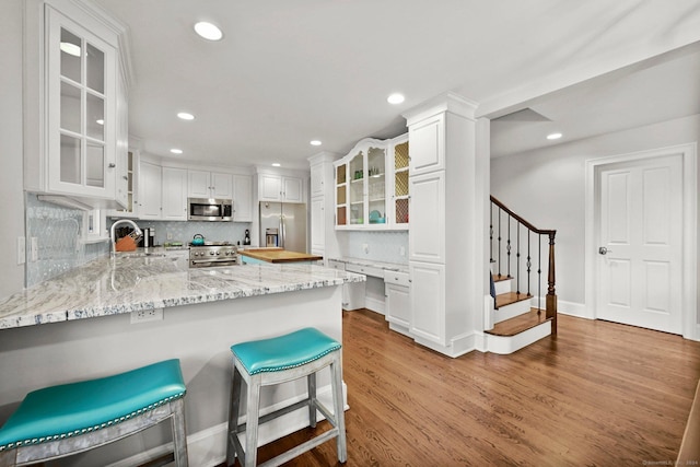 35 Knollcrest Rd, New Fairfield, CT 06812 - kitchen with stainless steel appliances, light wood-style floors, a sink, a peninsula, and backsplash