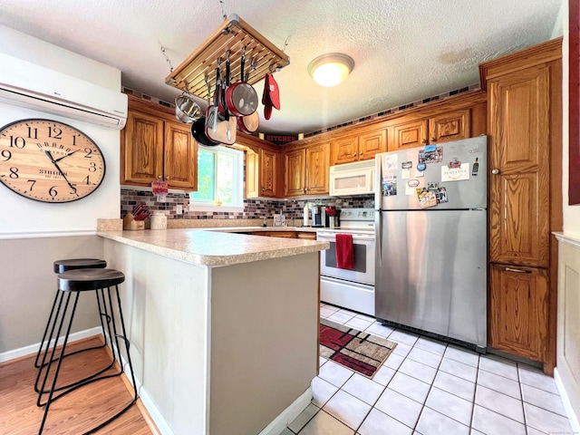 925 Oronoke Rd Unit 36G, Waterbury, CT 06708 - kitchen featuring white appliances, a peninsula, an AC wall unit, light countertops, and brown cabinets