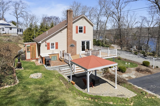 73 Lake Shore Dr, East Haddam, CT 06415 - back of house featuring a deck, a chimney, a lawn, a patio area, and a shingled roof