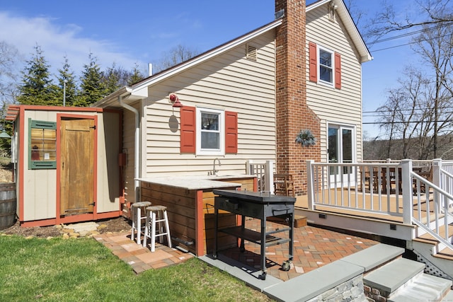 73 Lake Shore Dr, East Haddam, CT 06415 - back of house featuring a chimney, a wooden deck, and a patio