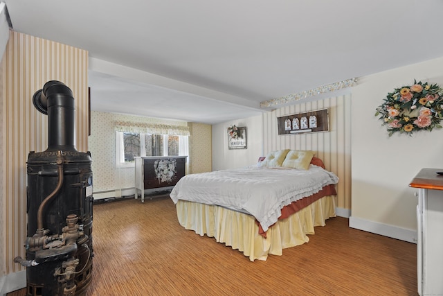 73 Lake Shore Dr, East Haddam, CT 06415 - bedroom featuring wood finished floors, wallpapered walls, a wood stove, baseboards, and a baseboard heating unit