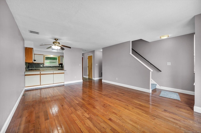 129 Knowles Ave Unit 129, Middletown, CT 06457 - unfurnished living room featuring wood-type flooring, ceiling fan, stairway, baseboards, and a textured ceiling