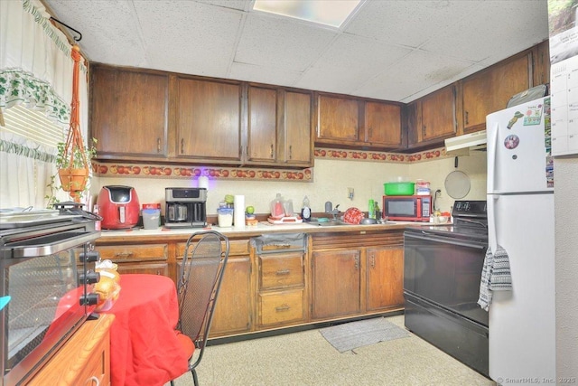 124 Main St, Sprague, CT 06330 - kitchen with freestanding refrigerator, black range with electric cooktop, stainless steel microwave, under cabinet range hood, and brown cabinetry