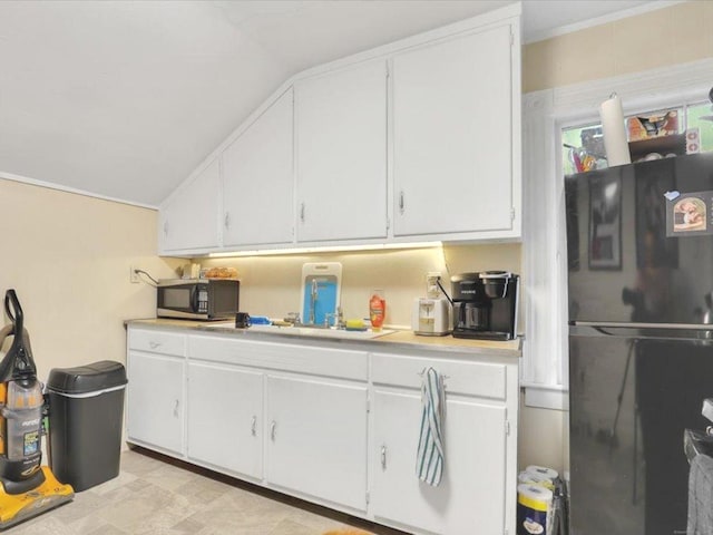 124 Main St, Sprague, CT 06330 - kitchen with freestanding refrigerator, light countertops, vaulted ceiling, and white cabinetry