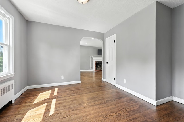 103 Anthony St, New Haven, CT 06515 - spare room featuring radiator, wood finished floors, arched walkways, and a fireplace