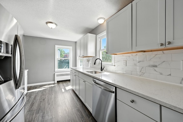 103 Anthony St, New Haven, CT 06515 - kitchen with appliances with stainless steel finishes, radiator, healthy amount of natural light, backsplash, and a textured ceiling