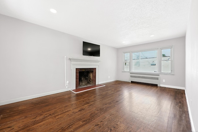 103 Anthony St, New Haven, CT 06515 - unfurnished living room with radiator, a brick fireplace, wood finished floors, a textured ceiling, and recessed lighting