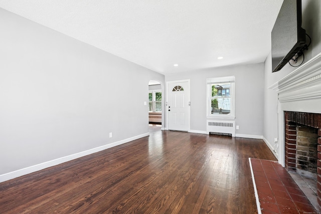103 Anthony St, New Haven, CT 06515 - unfurnished living room featuring radiator heating unit, a fireplace with flush hearth, arched walkways, wood finished floors, and recessed lighting