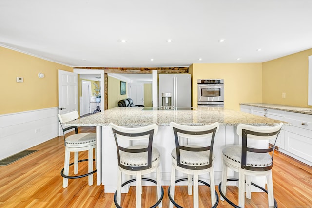 120 Huntington St, Shelton, CT 06484 - kitchen with stainless steel refrigerator with ice dispenser, white cabinets, light wood-style flooring, a spacious island, and wainscoting