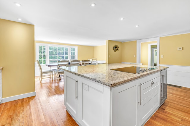 120 Huntington St, Shelton, CT 06484 - kitchen featuring black electric stovetop, beverage cooler, light wood-type flooring, a center island, and white cabinets