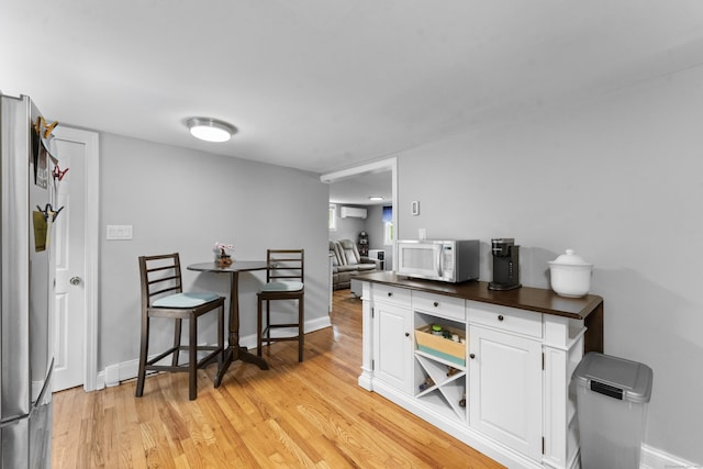 188 W Main St, East Lyme, CT 06357 - kitchen featuring white microwave, white cabinetry, light wood-type flooring, and freestanding refrigerator