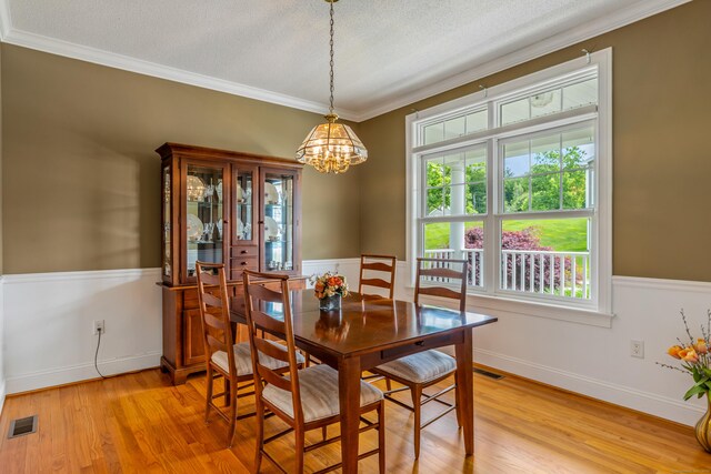 9 Benjamin Ln Unit 9, Tolland, CT 06084 - dining area featuring a chandelier, light wood-style floors, crown molding, a textured ceiling, and wainscoting