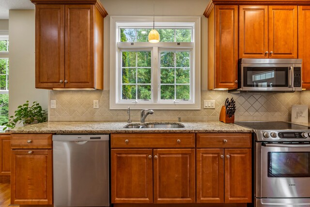 9 Benjamin Ln Unit 9, Tolland, CT 06084 - kitchen featuring appliances with stainless steel finishes, a sink, backsplash, light stone counters, and brown cabinetry