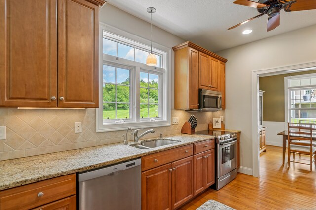 9 Benjamin Ln Unit 9, Tolland, CT 06084 - kitchen featuring stainless steel appliances, a sink, light wood-type flooring, brown cabinetry, and light stone counters