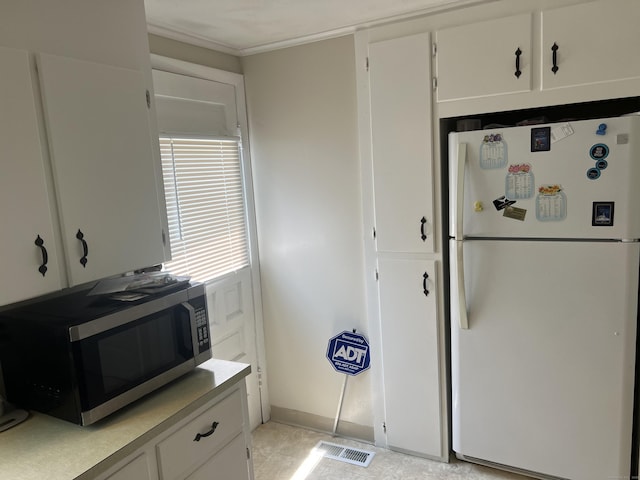 323 Harland Rd, Norwich, CT 06360 - kitchen featuring freestanding refrigerator, stainless steel microwave, white cabinetry, light countertops, and crown molding