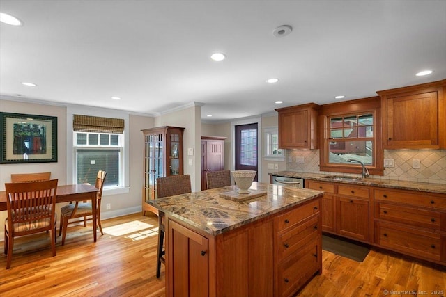 10 Point Beach Dr, Milford, CT 06460 - kitchen featuring brown cabinets, ornamental molding, stainless steel dishwasher, a breakfast bar, and light wood-type flooring
