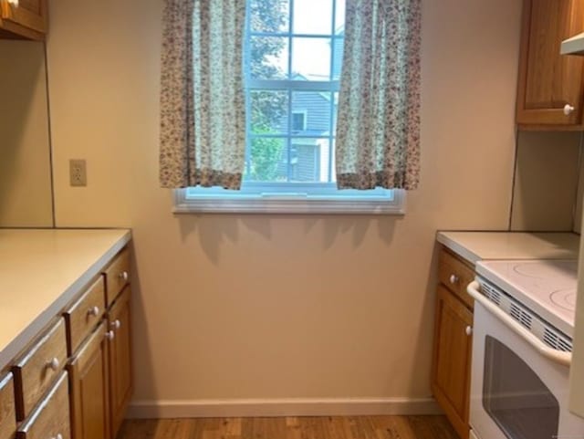 749 Long Hill Rd Unit A, Middletown, CT 06457 - kitchen featuring brown cabinetry, white range with electric stovetop, light countertops, light wood-style flooring, and baseboards