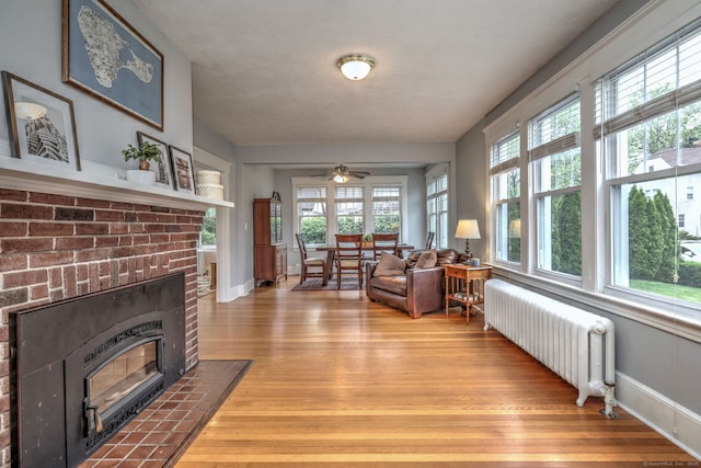 17 Norris St, Hamden, CT 06517 - living area with radiator heating unit, wood finished floors, a ceiling fan, and a brick fireplace