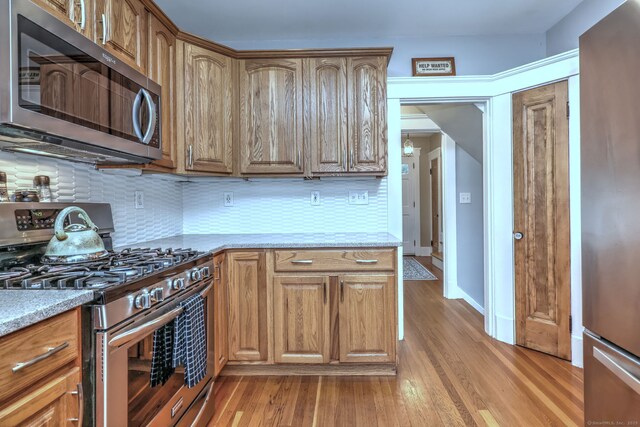 17 Norris St, Hamden, CT 06517 - kitchen featuring appliances with stainless steel finishes, light wood-type flooring, decorative backsplash, and brown cabinetry