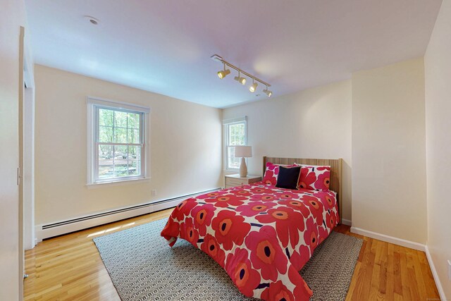 305 Thayer Pond Rd, Wilton, CT 06897 - bedroom featuring a baseboard radiator, multiple windows, wood finished floors, and rail lighting