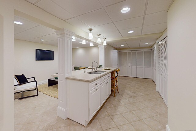 305 Thayer Pond Rd, Wilton, CT 06897 - kitchen with a sink, decorative columns, light countertops, white cabinetry, and light tile patterned floors
