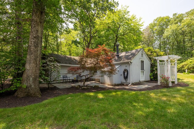 305 Thayer Pond Rd, Wilton, CT 06897 - rear view of house featuring a yard, a patio area, roof with shingles, and an outbuilding