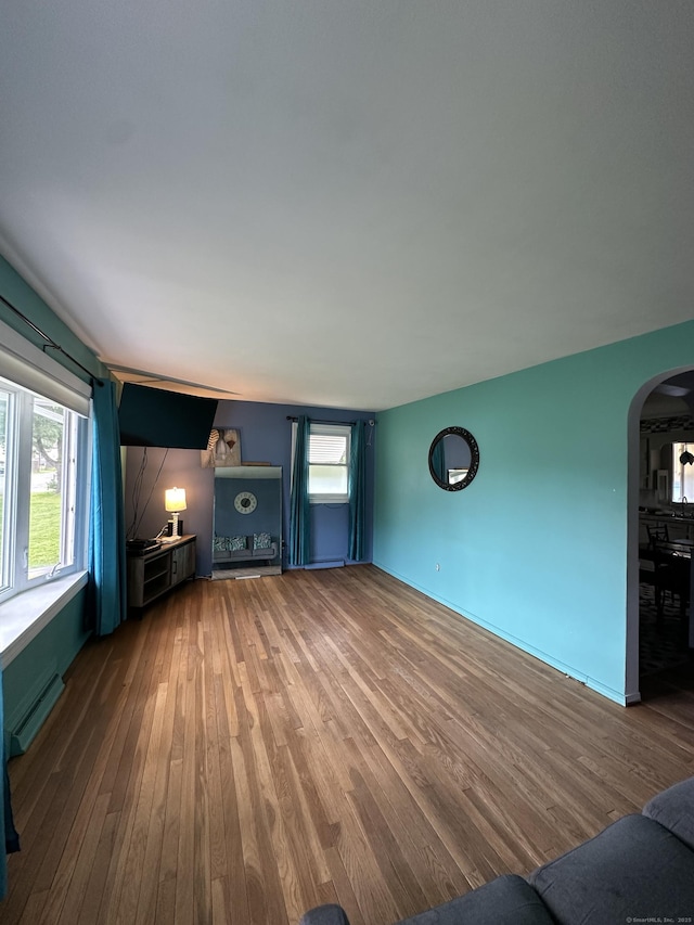 130 Judd Ave, New Britain, CT 06051 - unfurnished living room with arched walkways, wood finished floors, and a baseboard radiator
