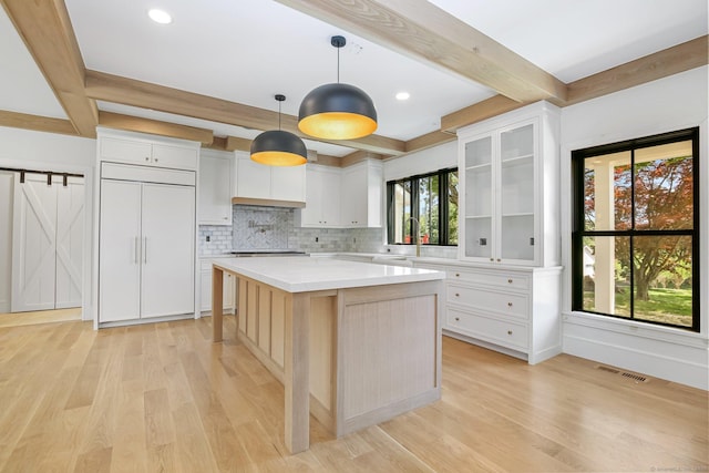 52 Garibaldi Ln, New Canaan, CT 06840 - kitchen with beam ceiling, light wood-style floors, light countertops, paneled fridge, and glass insert cabinets