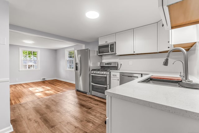 226 Quinn St, Naugatuck, CT 06770 - kitchen with appliances with stainless steel finishes, a sink, wood finished floors, baseboards, and white cabinets