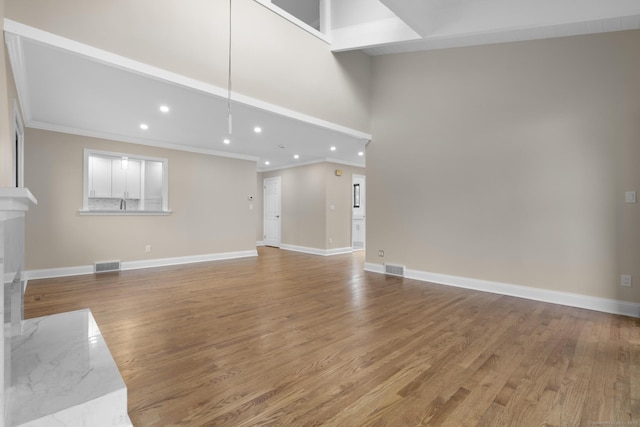 513 Opa Ln Unit B, Stratford, CT 06614 - unfurnished living room with crown molding, recessed lighting, baseboards, light wood-style floors, and a towering ceiling
