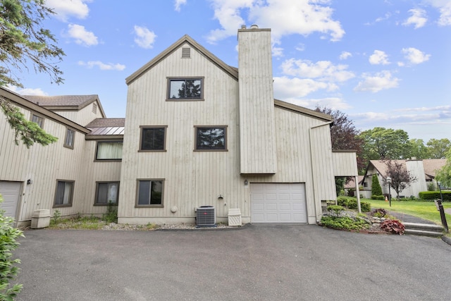 513 Opa Ln Unit B, Stratford, CT 06614 - view of side of home with a chimney, driveway, a garage, central AC unit, and metal roof