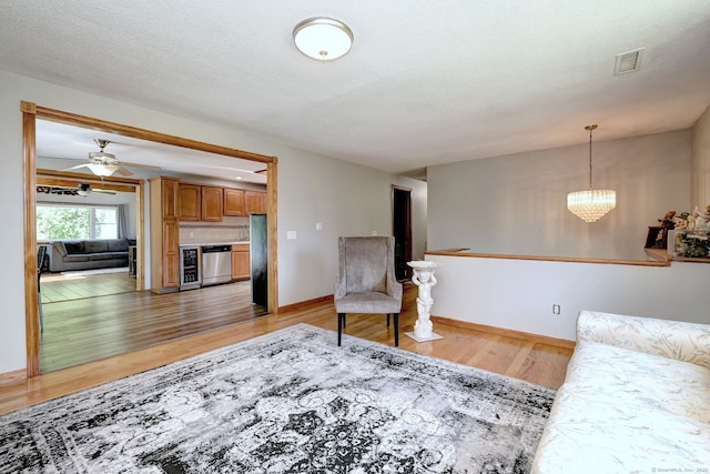 50 Sea Hill Rd, North Branford, CT 06471 - living room with light wood-style flooring, a chandelier, a textured ceiling, baseboards, and a ceiling fan