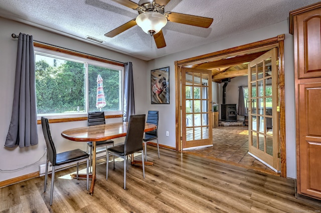 50 Sea Hill Rd, North Branford, CT 06471 - dining space featuring a wood stove, light wood-style flooring, a textured ceiling, baseboards, and ceiling fan