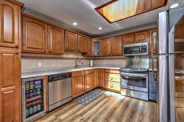 50 Sea Hill Rd, North Branford, CT 06471 - kitchen with appliances with stainless steel finishes, wine cooler, a sink, brown cabinetry, and light wood-type flooring