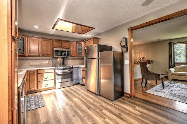 50 Sea Hill Rd, North Branford, CT 06471 - kitchen with appliances with stainless steel finishes, light countertops, light wood-style floors, glass insert cabinets, and brown cabinets