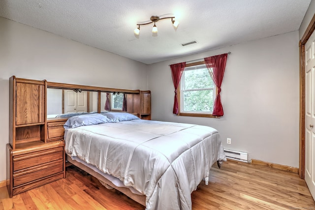 50 Sea Hill Rd, North Branford, CT 06471 - bedroom featuring a baseboard heating unit, light wood-style flooring, a textured ceiling, and baseboards