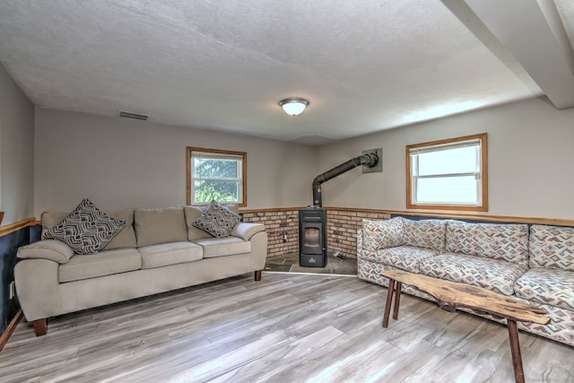 50 Sea Hill Rd, North Branford, CT 06471 - living area featuring light wood-type flooring, wainscoting, a wood stove, and a textured ceiling