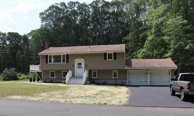 197 New Rd, Tolland, CT 06084 - split foyer home featuring driveway, a garage, a chimney, and a front lawn